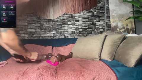 Media: A blurry photo shows a woman in a pink bra, using a black vibrator on a beige cushion, against a wall with a black-and-white textured mural.