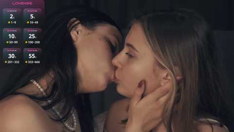 Media: A video shows two women passionately kissing, both with long hair, one with black hair and the other with blonde hair, both wearing blouses. A digital interface with stats and a countdown is in the background.