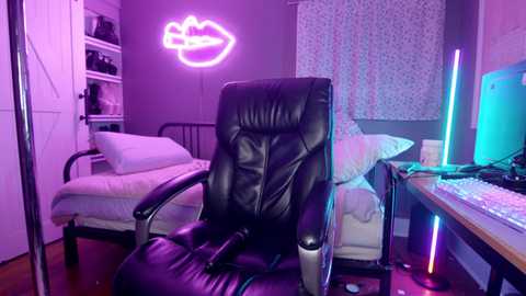 Media: A video of a neon-lit, minimalist bedroom with a black leather office chair, a bed with white sheets, a neon lips sign, and a desk with a computer monitor.