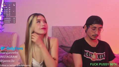 Media: Video of a young blonde woman in a white tank top and a young man in a black T-shirt and cap, both looking contemplative in a dimly lit room.