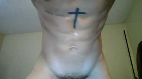 Media: Video of a fit, bare-chested man with a black cross tattoo on his chest, visible abs, and a small patch of pubic hair. Background is a beige wall and a door.