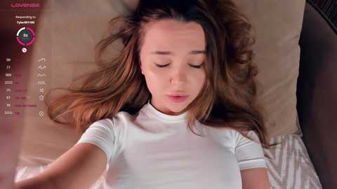 Media: A video of a young woman with long brown hair lying on a bed, eyes closed, wearing a white t-shirt, surrounded by a virtual reality interface.