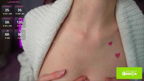 Media: Video of a fair-skinned woman with small pink hearts tattooed on her collarbone, wearing a white knitted cardigan. Health app interface in the background displays heart rate, temperature, and oxygen levels.