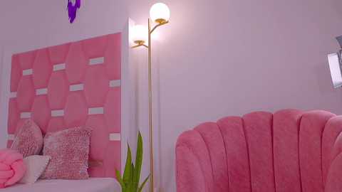 Media: Video of a modern, pastel-colored bedroom featuring a pink, upholstered headboard with a geometric pattern, a pink tufted chair, and a floor lamp with a white shade.