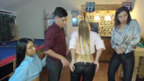 Media: Video of four people in a pool room: two women with long hair, two men in casual attire, one woman wearing a white top.