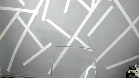 Media: Video of a modern, minimalist ceiling with white geometric shapes, intersecting lines, and a clear glass table or stand in the foreground.