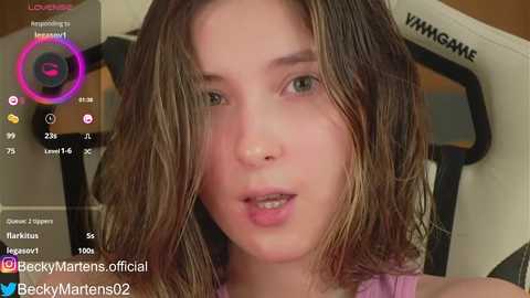 Media: A close-up video of a young woman with wet, shoulder-length brown hair, wearing a pink top, captured in a live stream on Twitch.