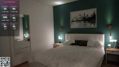 Media: A video of a modern, minimalist bedroom with a white bed, teal walls, and a black-and-white landscape painting above. The room features two bedside lamps, a mirror, and a QR code.