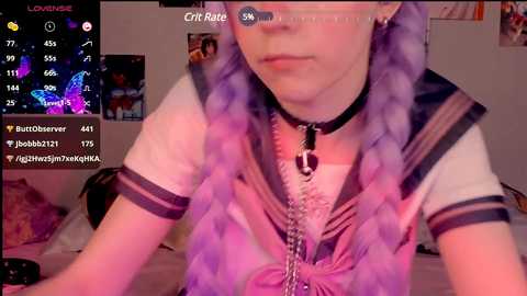 Media: Video of a young woman with long, lavender-dyed hair, wearing a sailor schoolgirl outfit, a black choker, and a pink bow, in a dimly lit bedroom, with a live-stream overlay displaying chat messages.