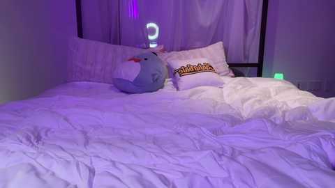 Media: A video of a purple-lit bedroom with a white bed, a plush penguin pillow, and a \"Bambi\" pillow, a crescent moon night light, and a green lamp.