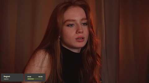 Media: A video of a young Caucasian woman with long, straight brown hair, wearing a black top, looking contemplative against a blurred, warm-toned background.