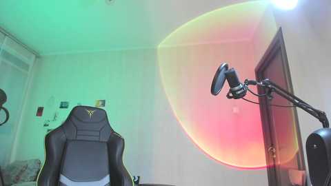 Media: Video of a gaming setup with a black gaming chair, a microphone stand, and a bright lens flare effect on a white wall.