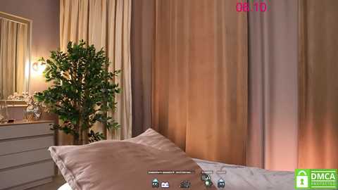 Media: A video of a cozy bedroom with beige curtains, a potted plant, a white dresser, and a bed with a plush pillow, all bathed in soft, warm lighting.