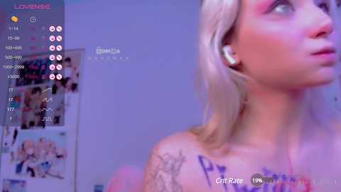 Media: Video of a young woman with blonde hair, visible tattoos on her shoulders, wearing headphones, standing against a purple wall with a messy background.