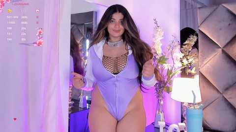 Media: Video of a curvy, light-skinned woman with long brown hair, wearing a tight, lavender bodysuit with a fishnet top, standing in a stylish bedroom with modern decor.