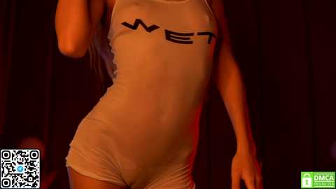 Media: Video of a woman wearing a tight, white, see-through tank top and matching shorts, highlighting her slender physique and small breasts. The background is dark, creating a dramatic contrast.