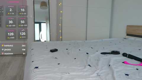 Media: Video of a modern, minimalist bedroom featuring a white bed with black and pink sex toys, a mirrored wardrobe, and a digital display showing fitness stats.