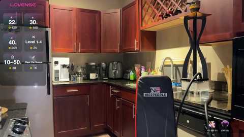 Media: Video of a cozy, modern kitchen with dark wooden cabinets, stainless steel appliances, a black gaming chair, and a digital scoreboard displaying health and energy levels.