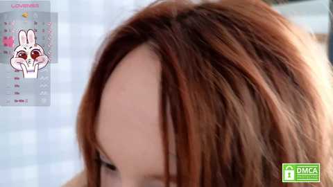 Media: Video of a close-up of a woman with shoulder-length, auburn hair. The image also includes a digital calendar with a white rabbit head and red heart icons.