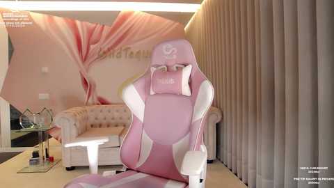 Media: Video of a pink gaming chair, beige sofa, and a large, pink and white floral wall mural in a modern living room with beige curtains and a glass coffee table.