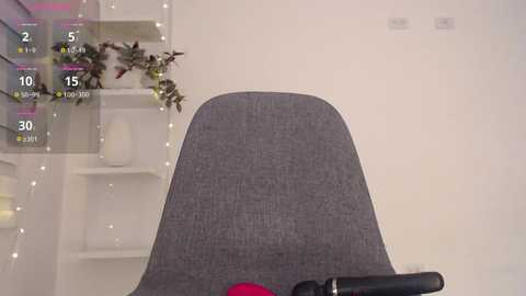 Media: Video of a modern office chair with a gray fabric seat, set against a minimalist white wall with a plant in a white pot.