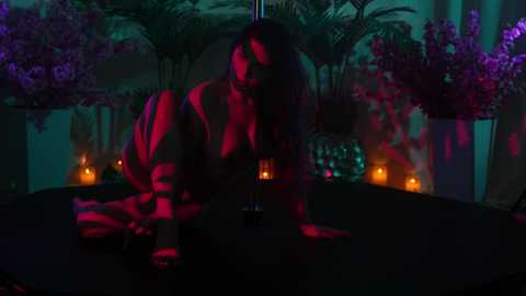 Media: Video of a woman in a black bra, leaning seductively over a pole in a dimly lit, exotic-themed room with purple and red lighting, candles, and lush greenery in the background.