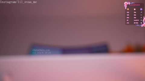 Media: A blurred video showing a pinkish wall with a blue strip and text, likely from a social media app, overlaid with an in-game chat box.