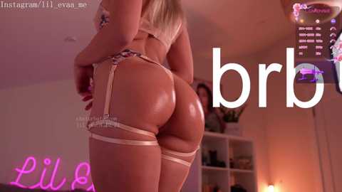 Media: Video of a blonde woman with tan skin in lingerie, garter belt, and thigh-high stockings, standing in a dimly lit room with a large \"bb\" watermark.