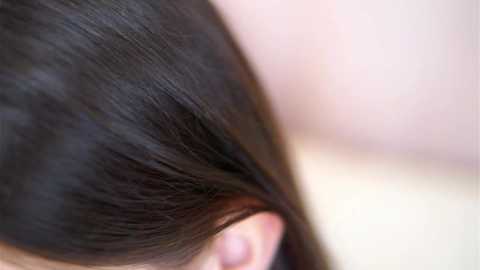 Media: Close-up video of a woman's dark brown, straight hair, showing the texture and shine. The background is blurred, emphasizing the hair.