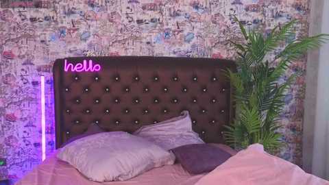 Media: Video of a cozy bedroom with a tufted, dark brown headboard, pastel bedding, and a vibrant, patterned wallpaper.