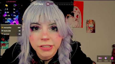 Media: A video of a young woman with pale skin, long silver hair, and bright makeup, looking directly at the camera. The background features a colorful room with posters and a virtual chat window.