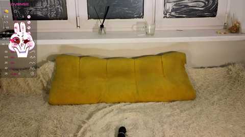 Media: A video of a cozy, modern room with a yellow cushion on a cream rug, white walls, and a calendar on the left.