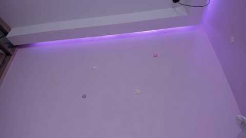 Media: A video of a bare, pale pink ceiling with four circular stickers of varying colors, a white ceiling light, and a wall-mounted electrical outlet.