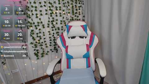 Media: Video of a white and blue gaming chair with adjustable armrests, surrounded by green ivy and fairy lights. A virtual overlay displays stats and a user's name, \"james123456789,\" in the corner.