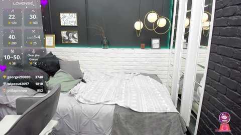 Media: Video of a modern, cozy bedroom with a white brick wall, black accent wall, grey striped duvet, grey pillows, and a white chair. Digital camera overlay shows camera settings and timestamp.