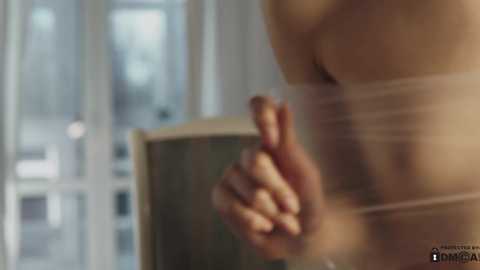 Media: A blurred video of a person giving a thumbs-up gesture, wearing a white bandage around their torso, with a blurred background of a modern indoor setting with windows.