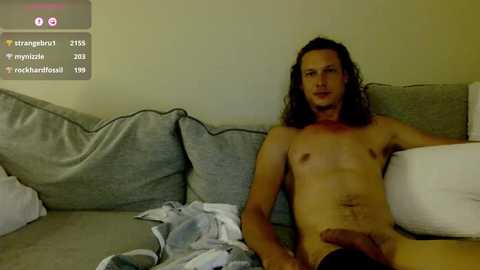 Media: A video shows a nude man with long hair, lying on a gray couch, with a visible erection.