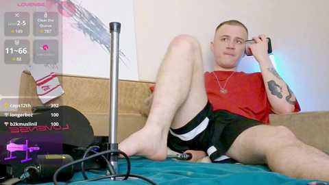 Media: Video of a bald man in a red shirt and black shorts, lounging on a couch with a gaming headset, surrounded by gaming peripherals.