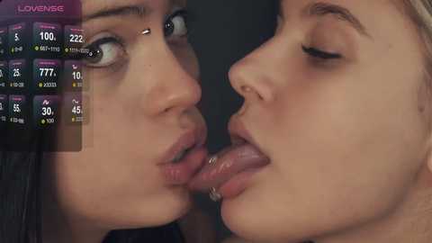 Media: A close-up video of two young women with light skin, dark hair, and full lips, kissing passionately. The background is blurred, emphasizing their faces. A weather forecast overlay shows rain and temperatures.