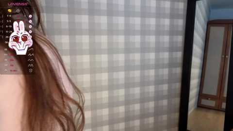 Media: Video of a young woman's long brown hair, partially visible, with a white bunny filter overlay. Background features a checkered wall and a wooden mirror in a dimly lit room.