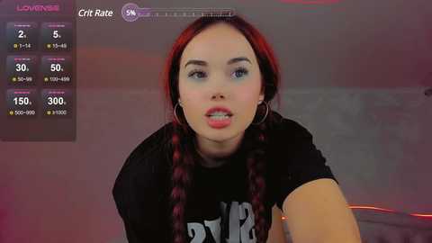 Media: A video of a young woman with red hair, wearing a black shirt, and a casual expression. The background shows a gaming screen with stats and a \"Lover\" rating.