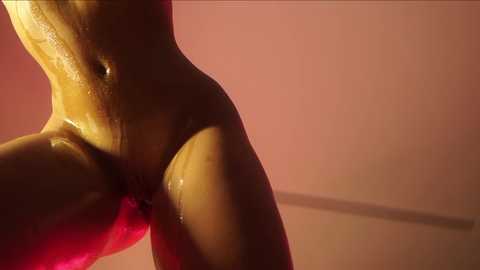 Media: Video of a nude woman's lower torso, glistening with water droplets, against a pink background. Her skin tone is a warm, caramel hue, emphasizing a curvy physique.