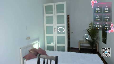 Media: A video of a modern bedroom with white walls, a white bed with pink pillows, a large white wardrobe, a green potted plant, and a QR code overlay showing weather data.