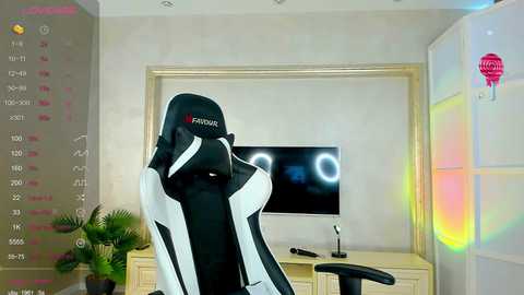 Media: A video of a gaming setup featuring a black and white gaming chair with the Prowin logo, a large flat-screen TV, and a desk with a monitor, keyboard, and mouse. The room has a modern, minimalist decor with a colorful LED light strip.