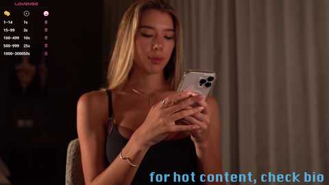 Media: A video of a blonde woman in a black dress, holding a smartphone, with a \"for hot content, check big\" text overlay.