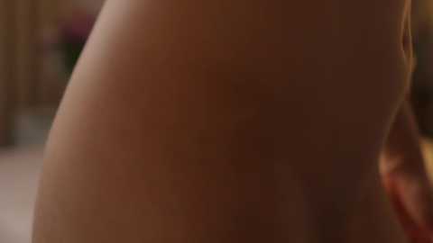 Media: Video of a close-up of a naked person's buttocks with a blurred background of flowers and foliage, showcasing a smooth, light skin tone.