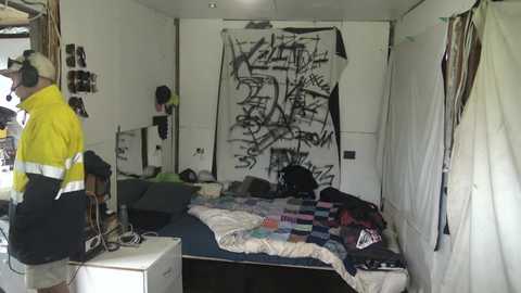 Media: Video of a cluttered, messy bedroom with a large, abstract black and white mural, yellow-and-black striped shirt, and various items strewn about.