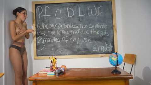 Media: Video of a nude woman with light brown skin and dark hair, standing in a classroom, facing a chalkboard with scientific formulas.