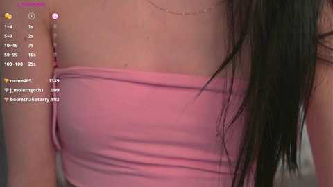 Media: Video of a woman with long, straight black hair wearing a pink strapless dress, showcasing her bare shoulders. Social media app icons are overlaid on the image.