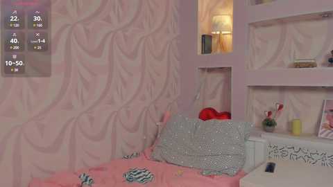 Media: Video of a pink-themed, whimsical bedroom with a floral wallpaper backdrop, featuring a bed with a striped duvet, a nightstand with a lamp, and a shelf with decorative items.